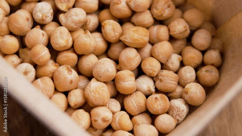 Dried chickpeas in cardboard packaging. Organic garbanzo ingredient. Top view. Rotation Dried chickpeas in cardboard packaging. Organic garbanzo ingredient. Top view. Rotation