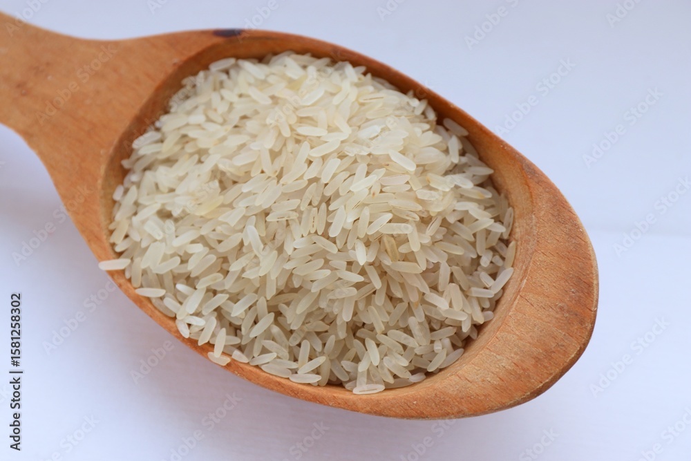 White rice in a wooden spoon on white background, close-up — concept of natural nutrition, visual purity and culinary simplicity for healthy lifestyle White rice in a wooden spoon on white background, close-up — concept of natural nutrition, visual purity and culinary simplicity for healthy lifestyle