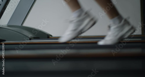 Athletic woman running on a treadmill in modern gym. Fit girl doing cardio workout on a running machine in fitness center. Focused female training indoors to stay healthy and fit.
