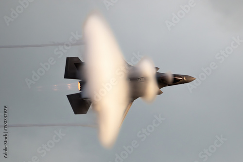 Modern fighter jet flying fast causing a vapor cone.
