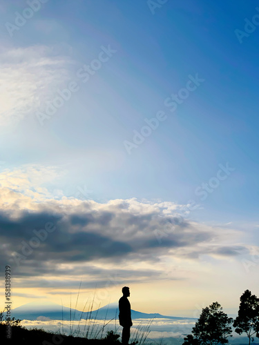 Photography A lone silhouette of a person standing on a hilltop, gazing at the expansive sky