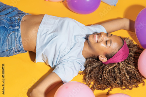 Young woman lying down and having fun with colorful balloons