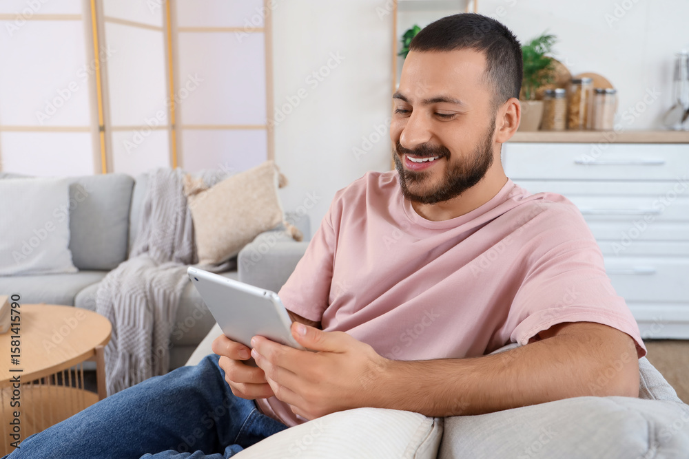 Young man using tablet computer on sofa at home Young man using tablet computer on sofa at home