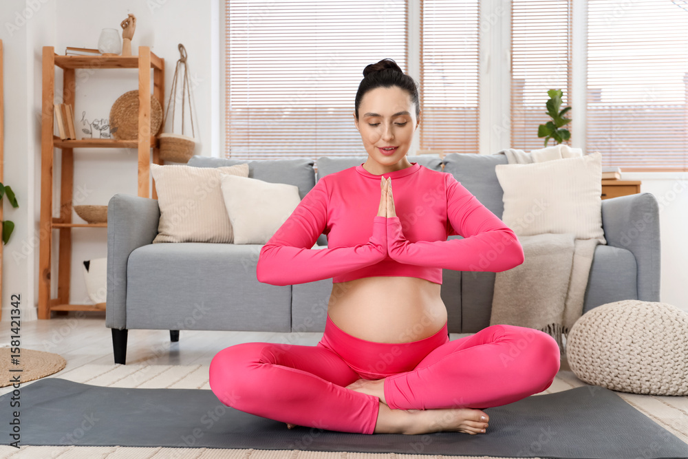 Obraz premium Sporty pregnant woman meditating on yoga mat at home