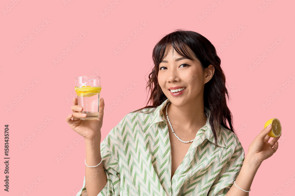 Young Asian woman with citrus infused water on pink background Young Asian woman with citrus infused water on pink background
