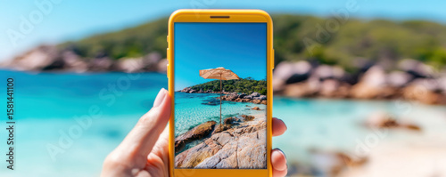 Vibrant beach scene captured on smartphone, showcasing sun umbrella on rocky shore