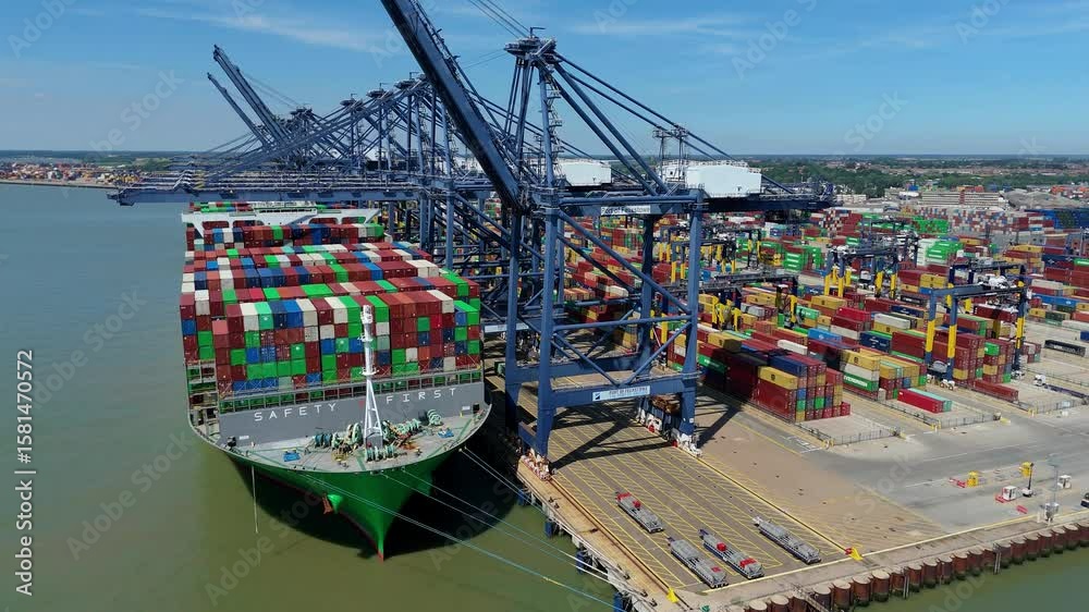 Aerial drone shot Felixstowe busy port cargo ships, shipping containers, huge cranes, loading and unloading heavy goods vehicles summer maritime business England UK.