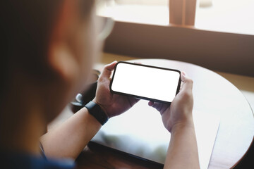Fotobehang Cappuccinokleur A person holding a smartphone horizontally with a blank white screen. A perfect mockup for showcasing landscape video, games, or streaming content.  © Thaspol