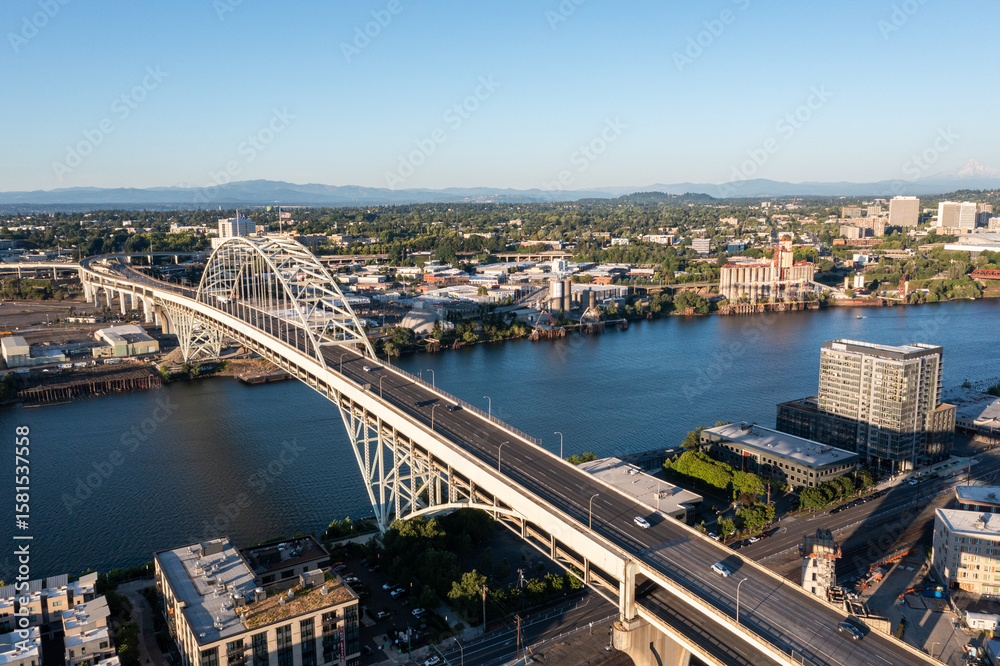 Obraz premium Aerial drone picture of Portland’s Fremont Bridge at sunset, the Willamette River, Downtown Portland, industrial area, and Mt. Hood in the background, with clear blue summer sky