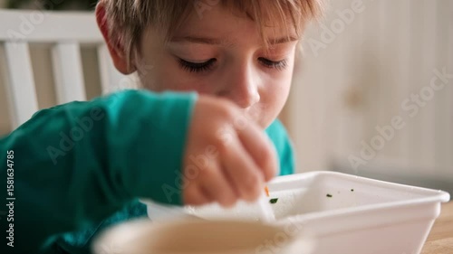 6 years old boy eats instant noodle from box. Child is eating spaghetti. Lunch time. A good appetite. Tasty children food. Close-up portrait. Carbs dinner. Fast food. Kid eating by himself with fork.