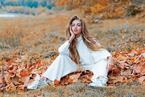 Autumn girl in good mood posing outdoor. Dreamy girl in fall. Beauty model, young beautiful woman hold autumn leaves. Romantic woman in autumn park. Autumn fall concept.
