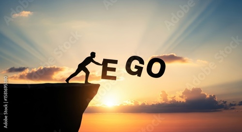 Silhouette figure pushing the word ego off a cliff at sunset in a conceptual image with bright sky