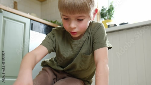 Cute little blonde child boy sitting on the floor playing with wooden toy train. Toddler kid plays railway. Made of natural materials. Birthday gift. Preschool employment. Brain, coordination exercise