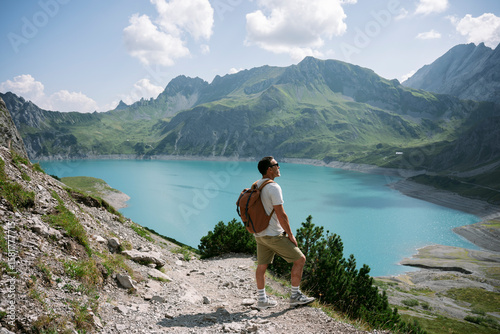Hiker admiring breathtaking lake and mountain view in the alps