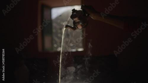 Slow motion close-up of Moroccan tea being served at sunset, warm light hitting the steam rising from the glass, creating a poetic and intimate atmosphere inside a traditional home in the Gran Atlas