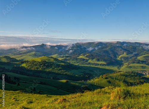Fototapeta Naklejka Na Ścianę i Meble -  Green mountain meadows with cattle. Mountain pass in Pieniny in Poland. Beautiful, dynamic and hazy sky over the mountains.Discover the beauty of spring's lush landscape and mountains.