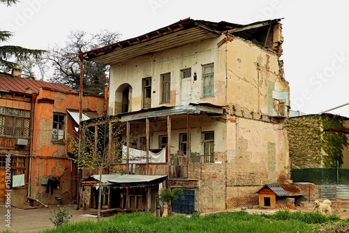 An old residential building with a lawn is falling into disrepair due to lack of proper maintenance in the center of Tbilisi