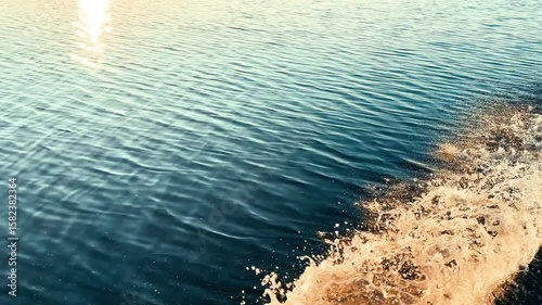 Moving fishing boat at the ocean with water splashes. Ocean sea water wave reflections. Motor boat in the lake at sunset