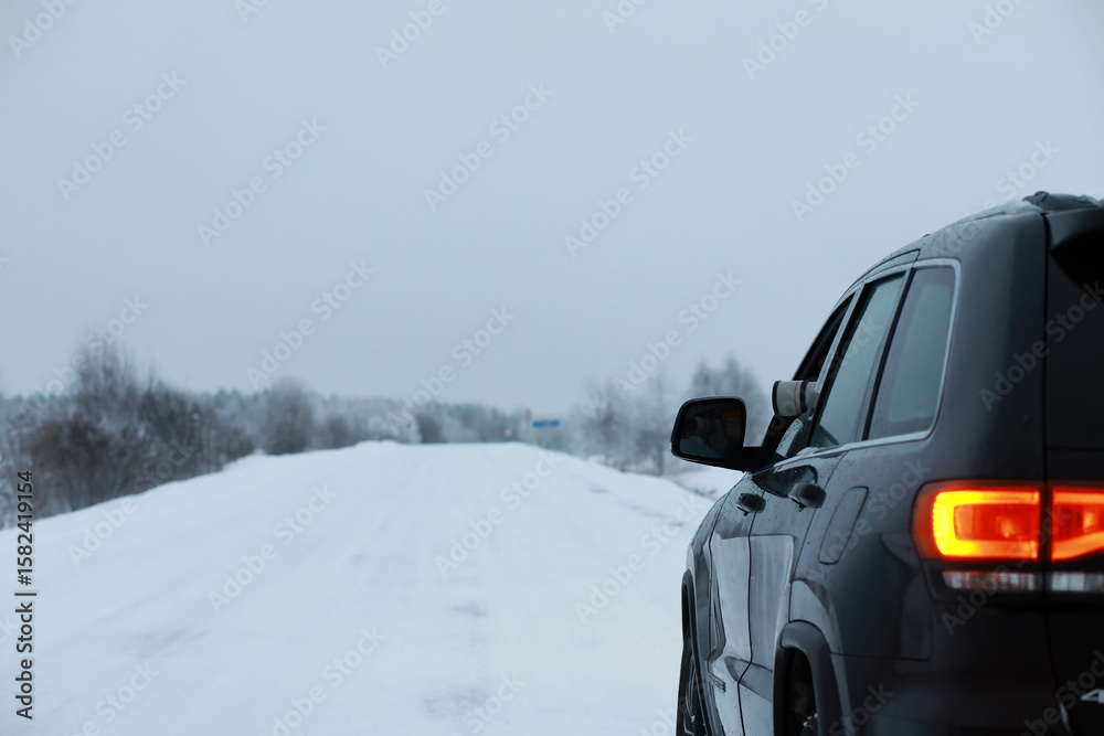 Naklejka premium Car in the winter forest. Traveling through a snowy park by car during the Christmas holidays.