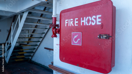 фотографія Red fire hose box on a passenger ship deck with stairs in the background