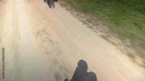 Silhouette of active cyclist riding on asphalt rural road, closeup photo. Bike, road and cyclist shadow on asphalt while riding. Outdoor travel, motion and summer sun.