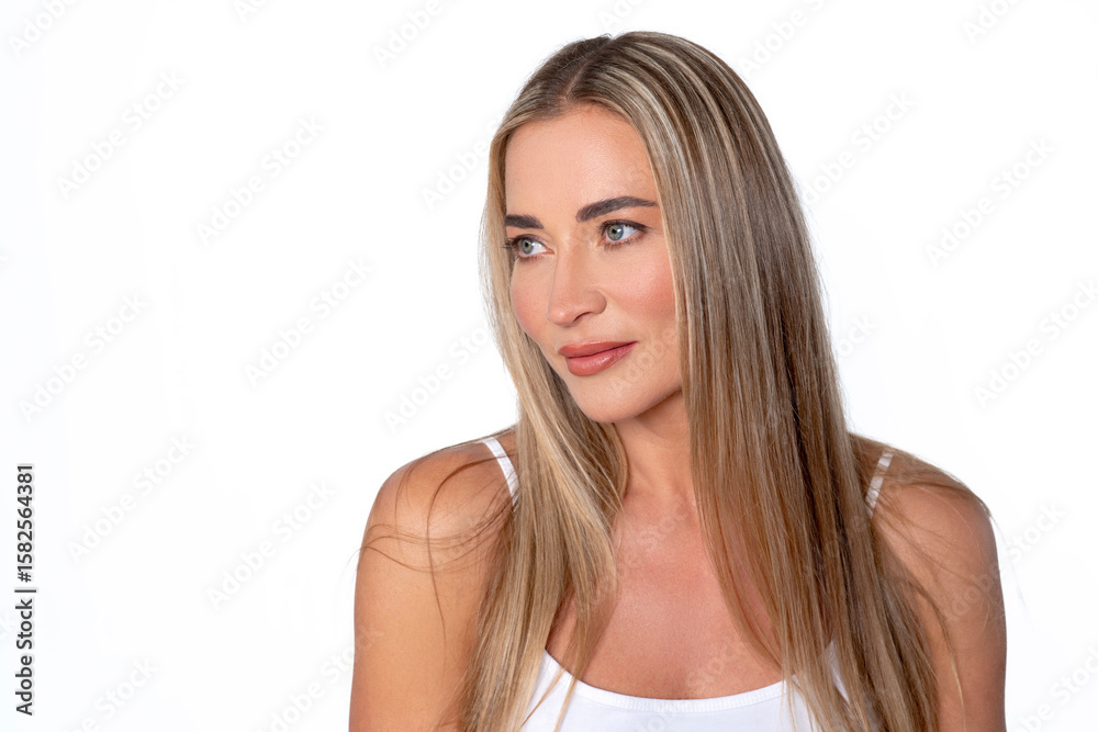 Portrait of a woman with long hair and a confident expression posing against a plain white background in a studio setting during daylight Portrait of a woman with long hair and a confident expression posing against a plain white background in a studio setting during daylight