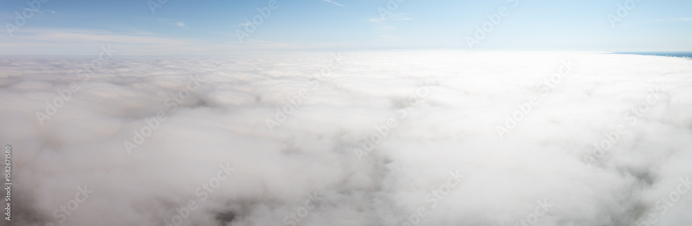 A high altitude perspective showing a vast layer of white clouds blending with the horizon, set beneath a clear blue sky with no visible landmarks. A high altitude perspective showing a vast layer of white clouds blending with the horizon, set beneath a clear blue sky with no visible landmarks.