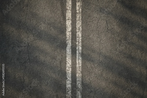 Weathered asphalt road surface with worn white double lines, creating a textured background from an overhead perspective, ideal for concepts of direction, journey, or urban decay.