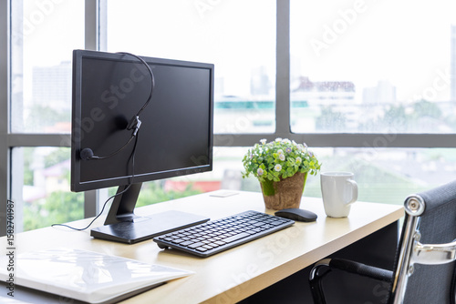 Call center desk with computer, headset, coffee mug, and potted plant in modern office