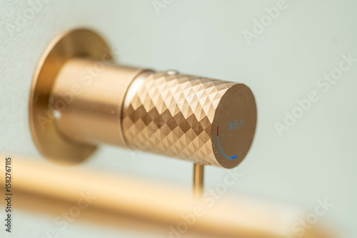 Close-up of luxury gold faucet handle — modern brushed brass texture with knurled grip, minimalist high-end bathroom design, hot & cold indicator, premium fixture detail