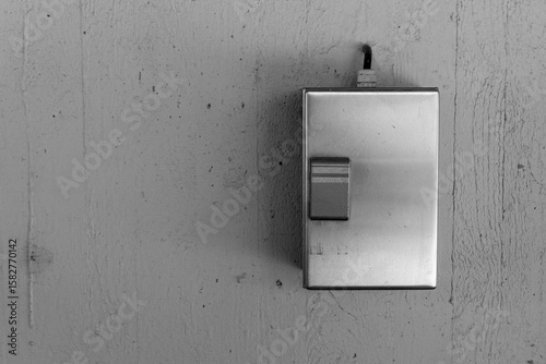 Metal switch plate on a textured wall illuminated by soft light brings a modern touch to minimalistic design aesthetics in a cozy space
