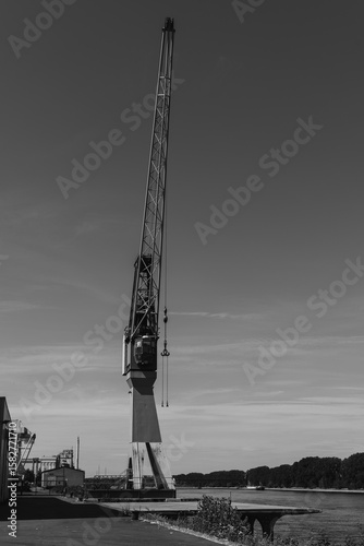 Industrial crane towers over the serene waterfront, capturing the essence of maritime life in a quiet harbor at dawn