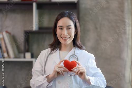 Asian female doctor holding a red heart in her hands in the concept of care your heart.