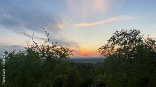 Sunrise time lapse on moving clouds on sky and rising sun. Czech landscape