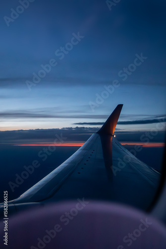 A stunning sunset view of an airplane wing above the clouds captured from a window seat during flight