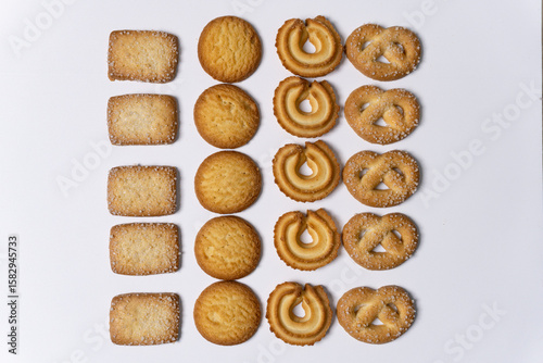 Assorted Danish butter cookies arranged on a white background, sprinkled with sugar crumbs. A classic selection featuring various shapes and textures, perfect for snack or dessert concepts.