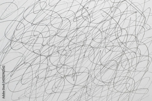 Chaotic energy: A close-up shot of dense, abstract pencil scribbles on white paper, creating a dynamic background texture.
