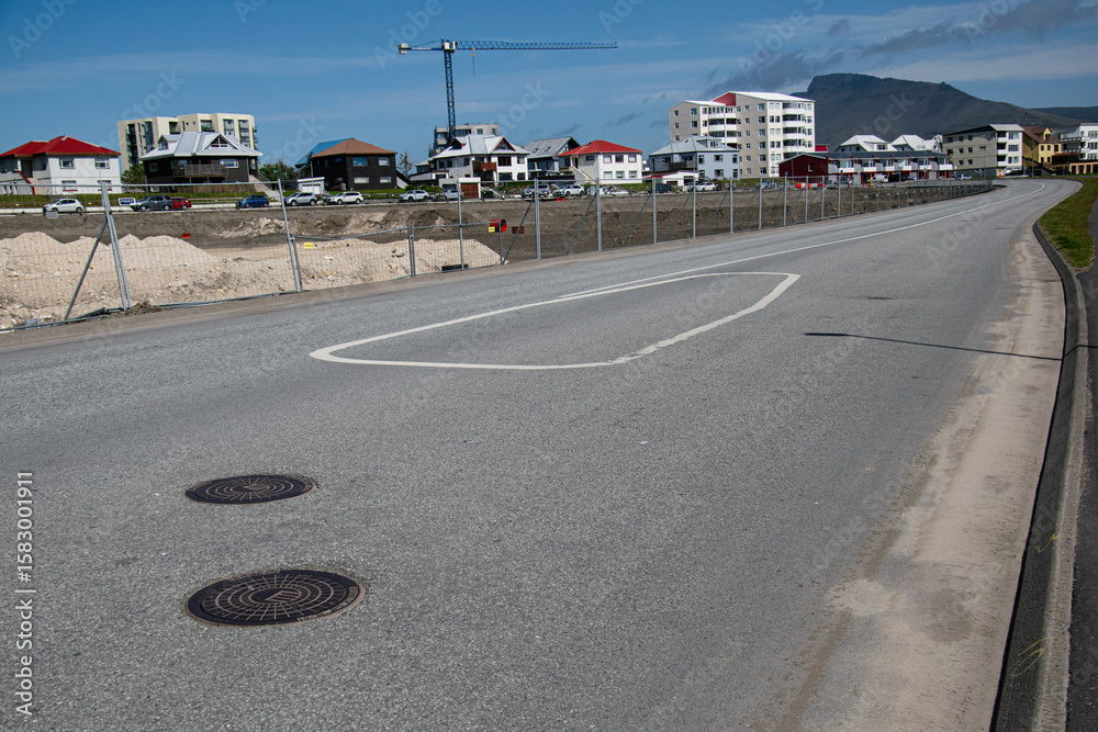 Fototapeta premium Scenic suburban Akranes road with modern housing and a mountain background