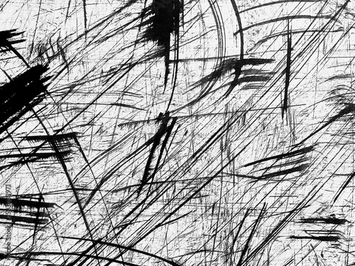 Abstract black and white texture with chaotic lines and patterns created by scratches on a surface