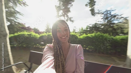 Young woman smiling and taking selfie video in park