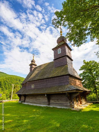 likitsary, transcarpathia, ukraine - 02 jul 2020: traditional wooden church architecture of europe. summer landscape in carpathian mountains. unique ruthenian religion heritage. side view