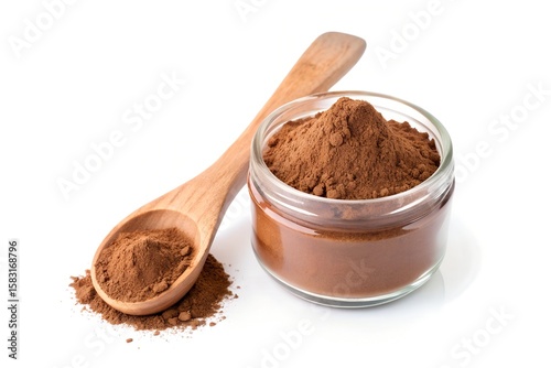 Carob powder in glass jar with wooden spoon on white background