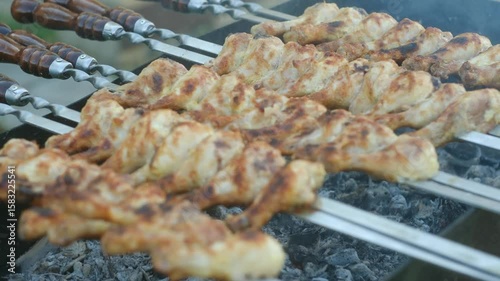 Sizzling chicken skewers grilling over hot charcoal, releasing fragrant smoke and promising delectable flavors of traditional outdoor summer cooking. Chicken skewers grilling on barbecue, smoke rising