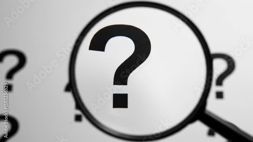 Magnifying glass focusing on a black question mark on a white background
