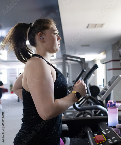 Real woman with a normal body working out on treadmill in gym. Realistic fitness and healthy weight loss motivation