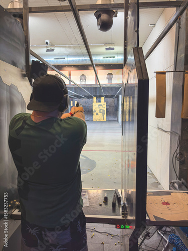 Canvastavla A man practices shooting at an indoor shooting range.