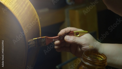 Obraz na płótnie Skilled luthier brushing dark varnish on wooden cello surface, highlighting meti