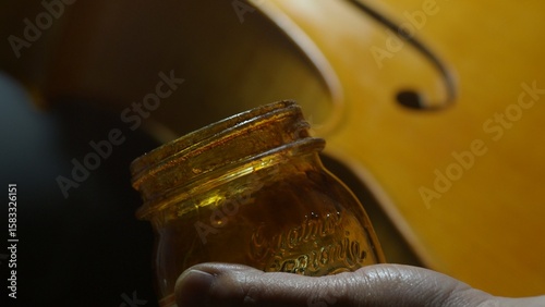Fotografie Skilled craftsman carefully brushing protective varnish layer onto wooden cello