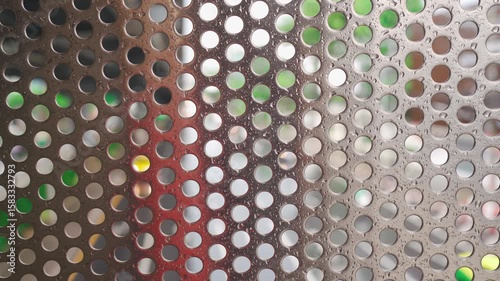 Urban rain scene: circular-patterned metal fence and traffic in Bangkok