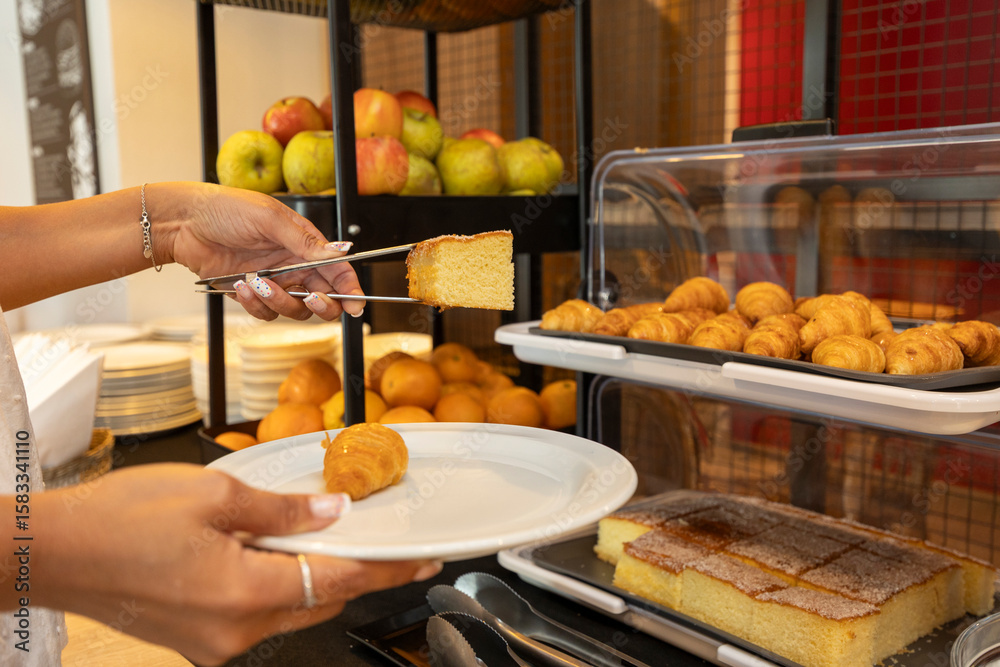 Naklejka premium Hotel guest picking a slice of pound cake from breakfast buffet